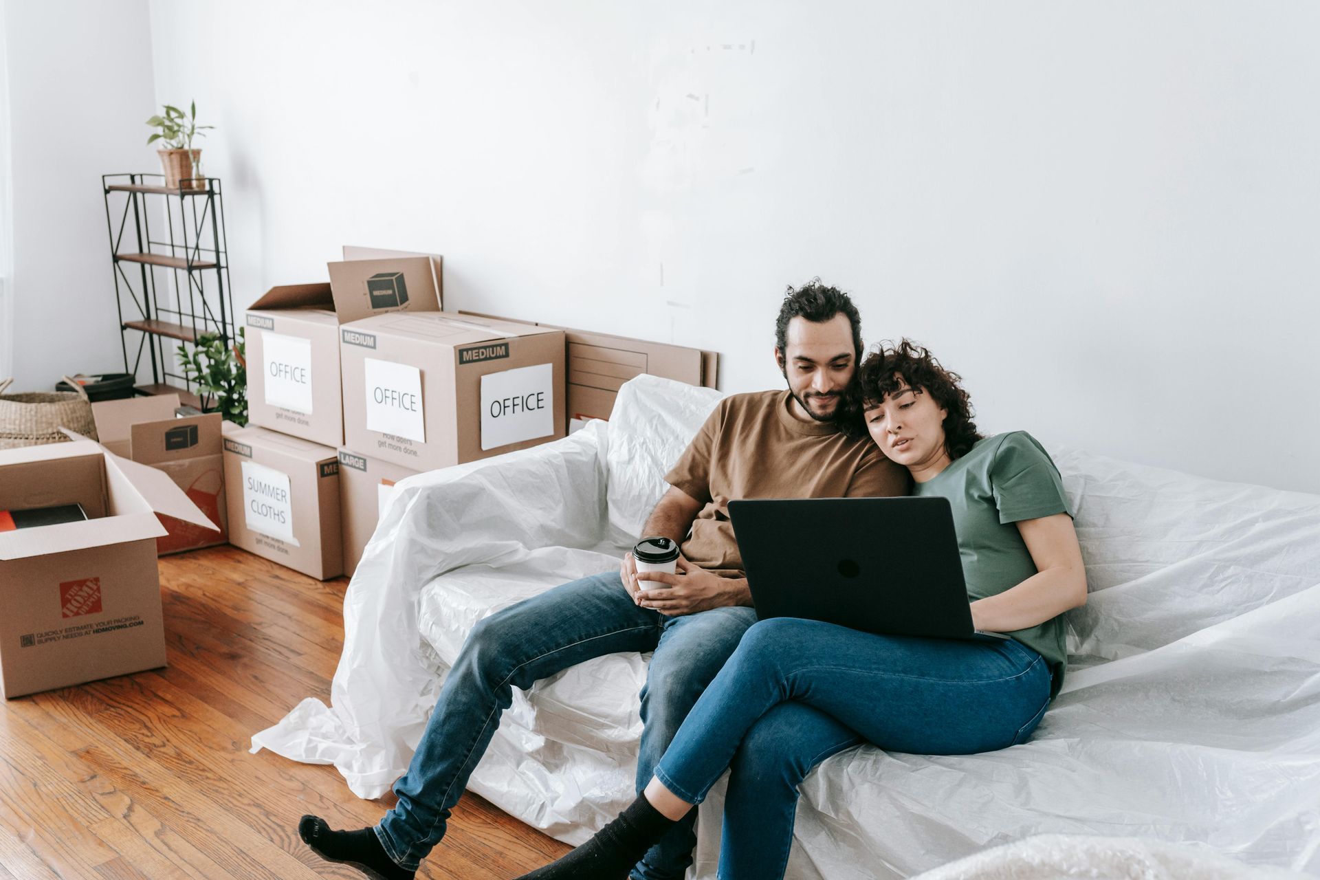 A man and a woman are sitting on a couch looking at a laptop.