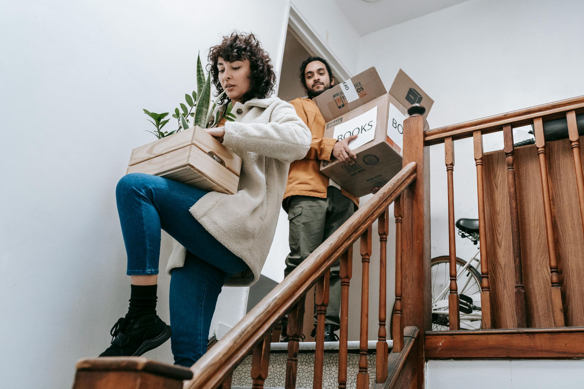 A man and a woman are carrying boxes up a set of stairs.