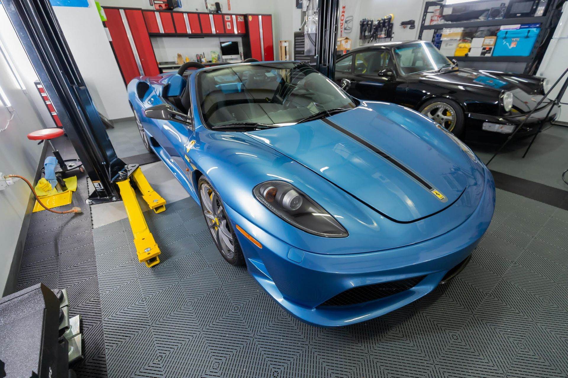 A blue sports car is parked on a lift in a garage.