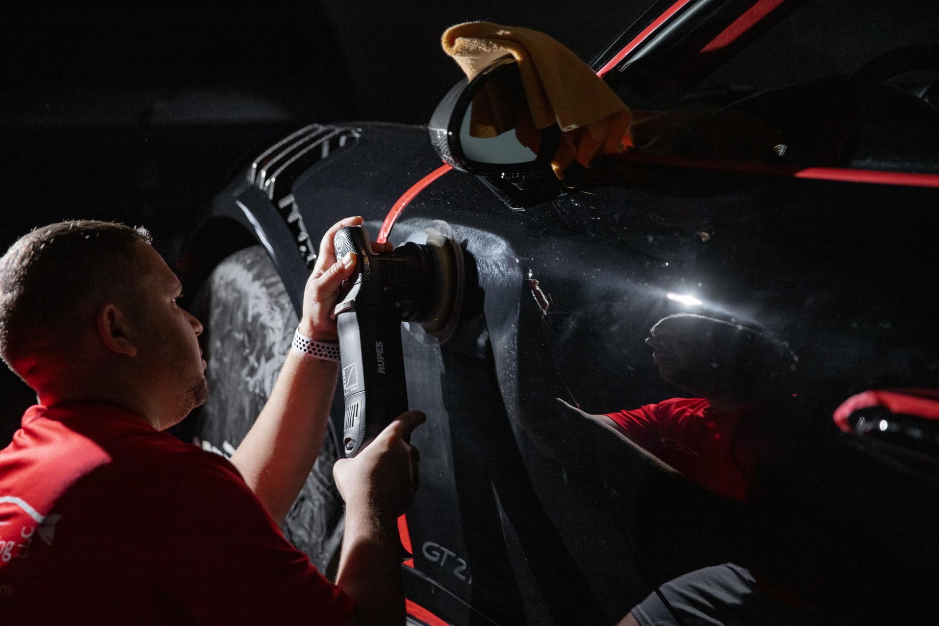 A man is polishing the side of a black car.