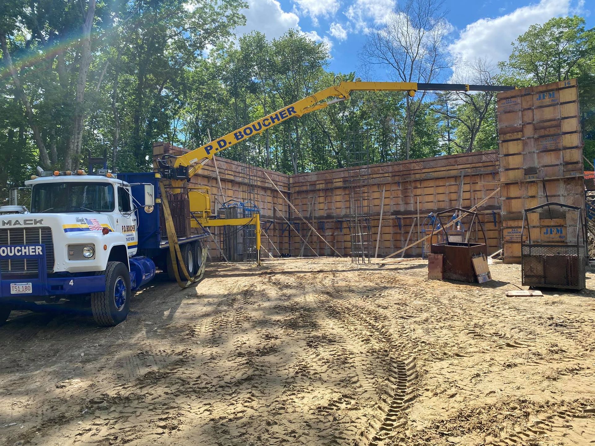Construction site with a truck, concrete forms, and an extended crane arm.