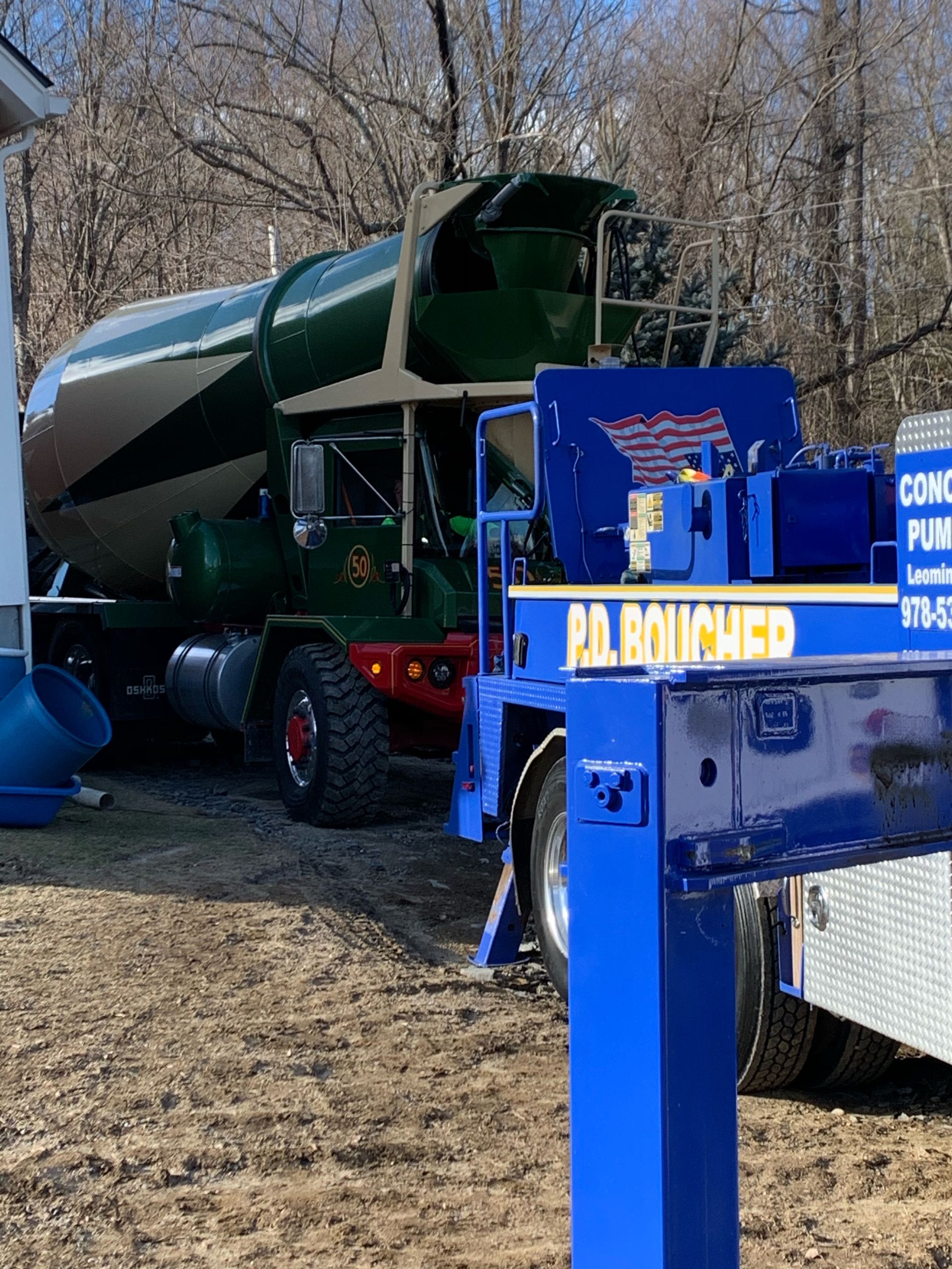 Cement truck with a green and tan drum, blue support structure, and red wheels.