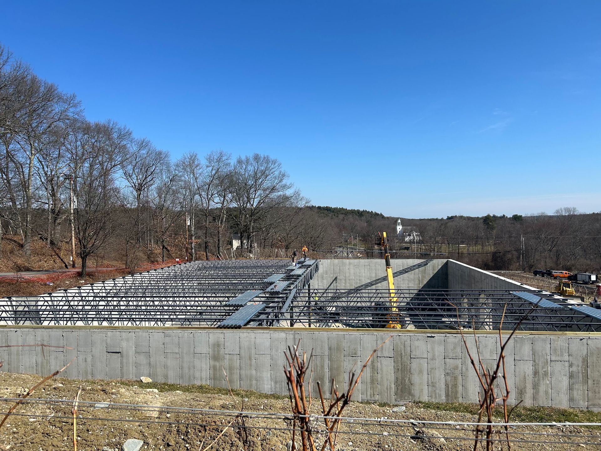 Construction site with concrete walls and steel framework under a clear blue sky.