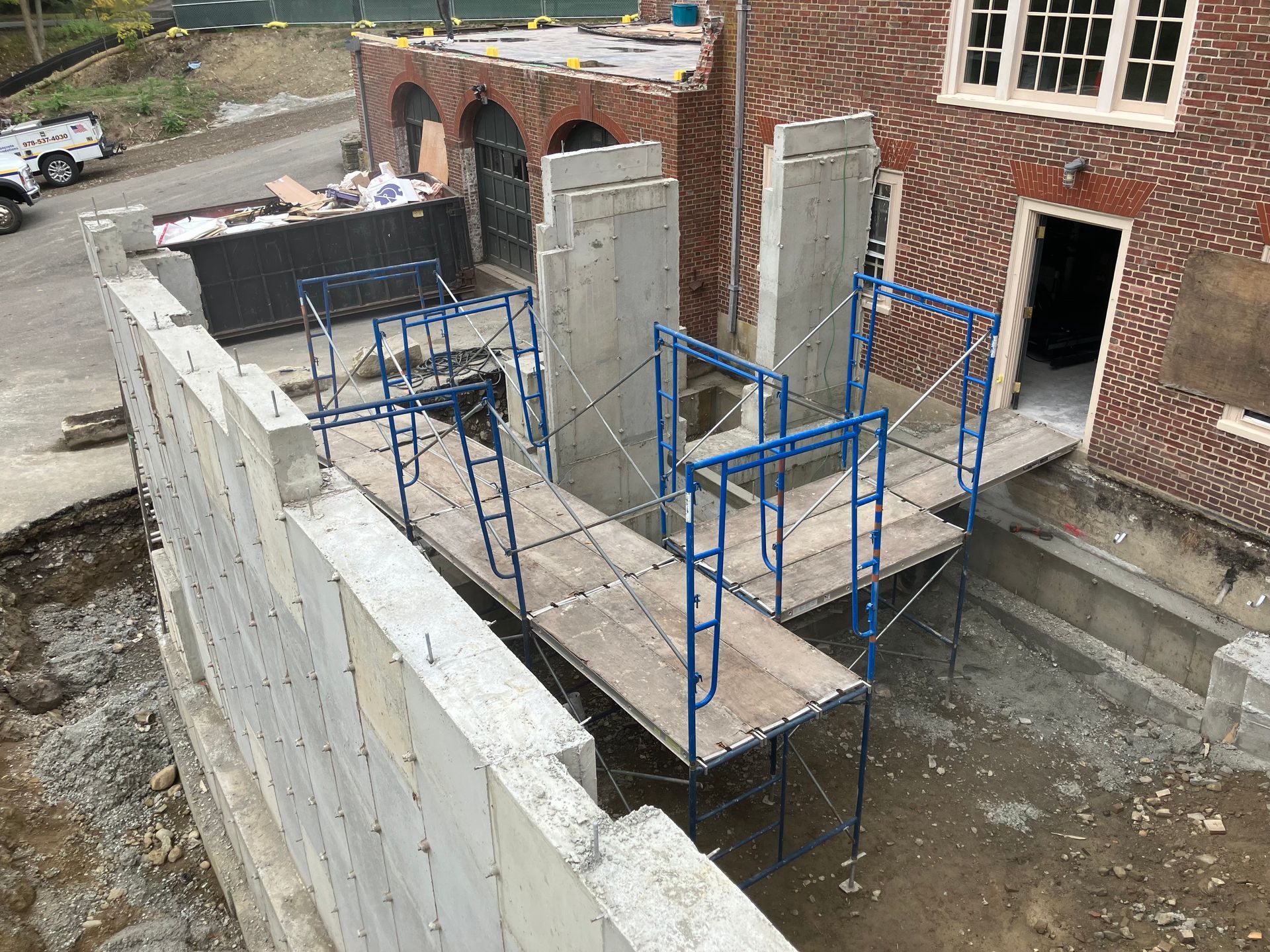 Construction site with scaffolding. Concrete walls and building with brick facade.