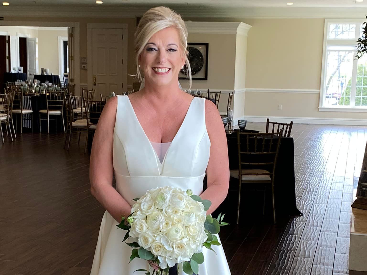 a bride in a white dress is holding a bouquet of white flowers .