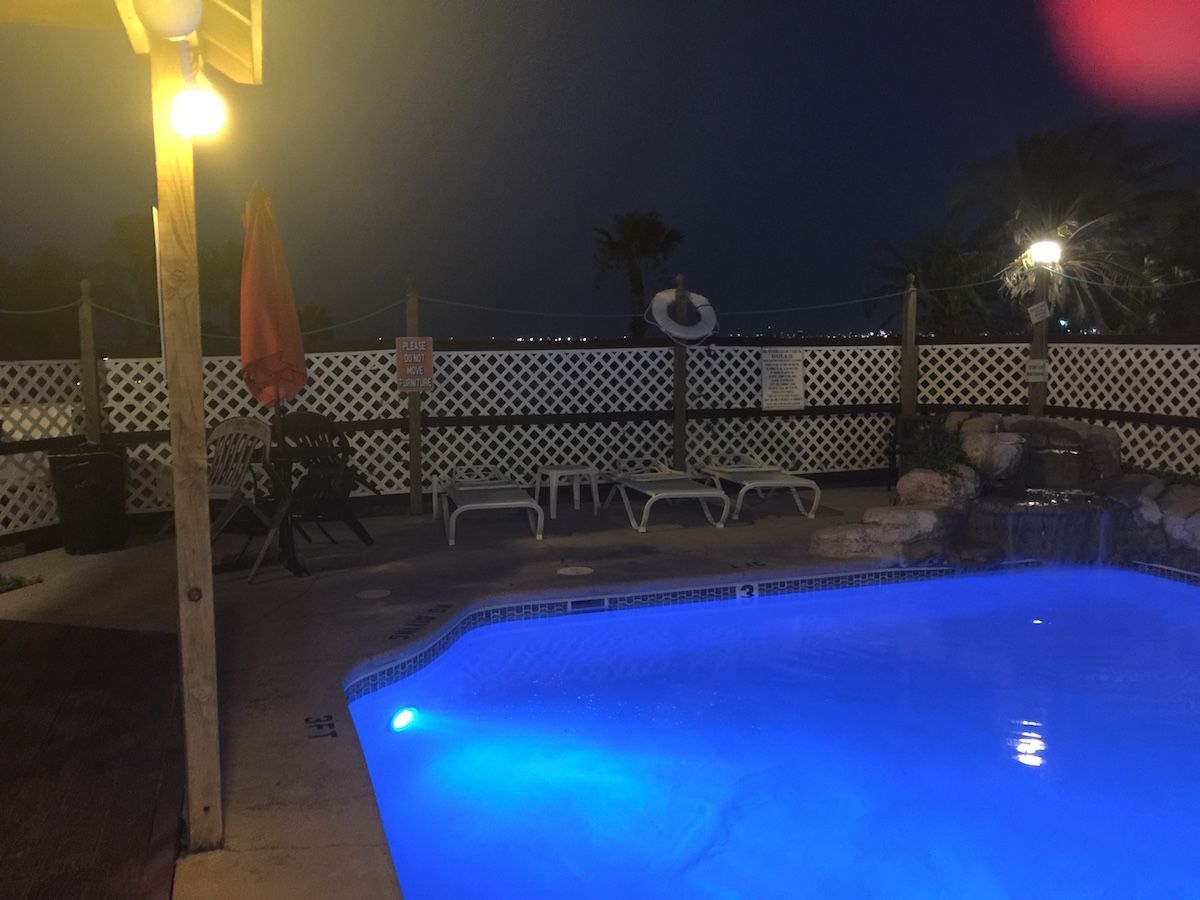 A swimming pool is lit up at night with blue lights.