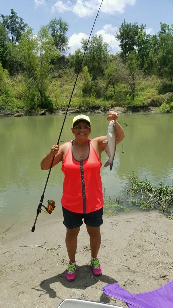 A woman is holding a fishing rod and a fish in her hand.