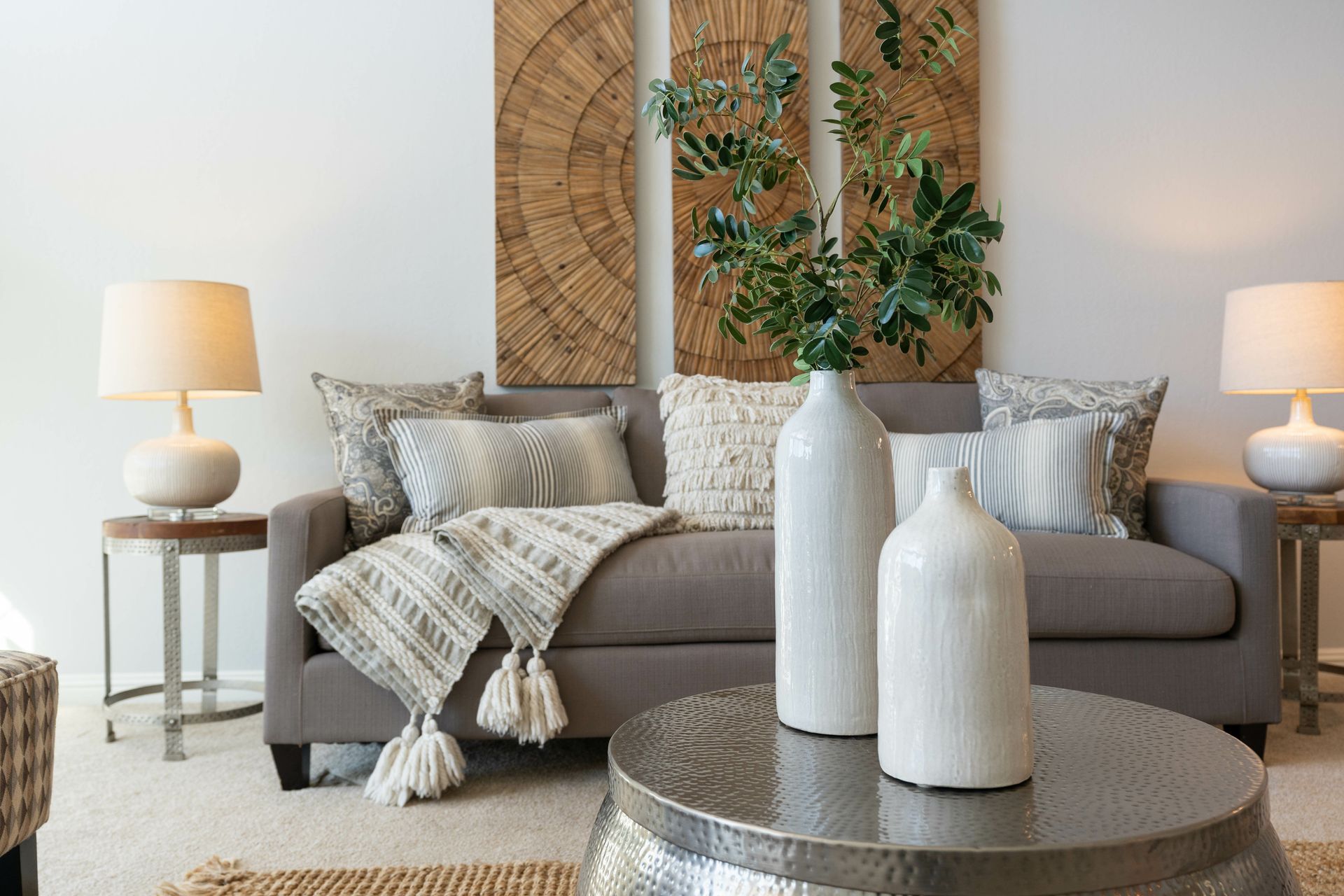 A living room with a couch , table , lamps and vases.