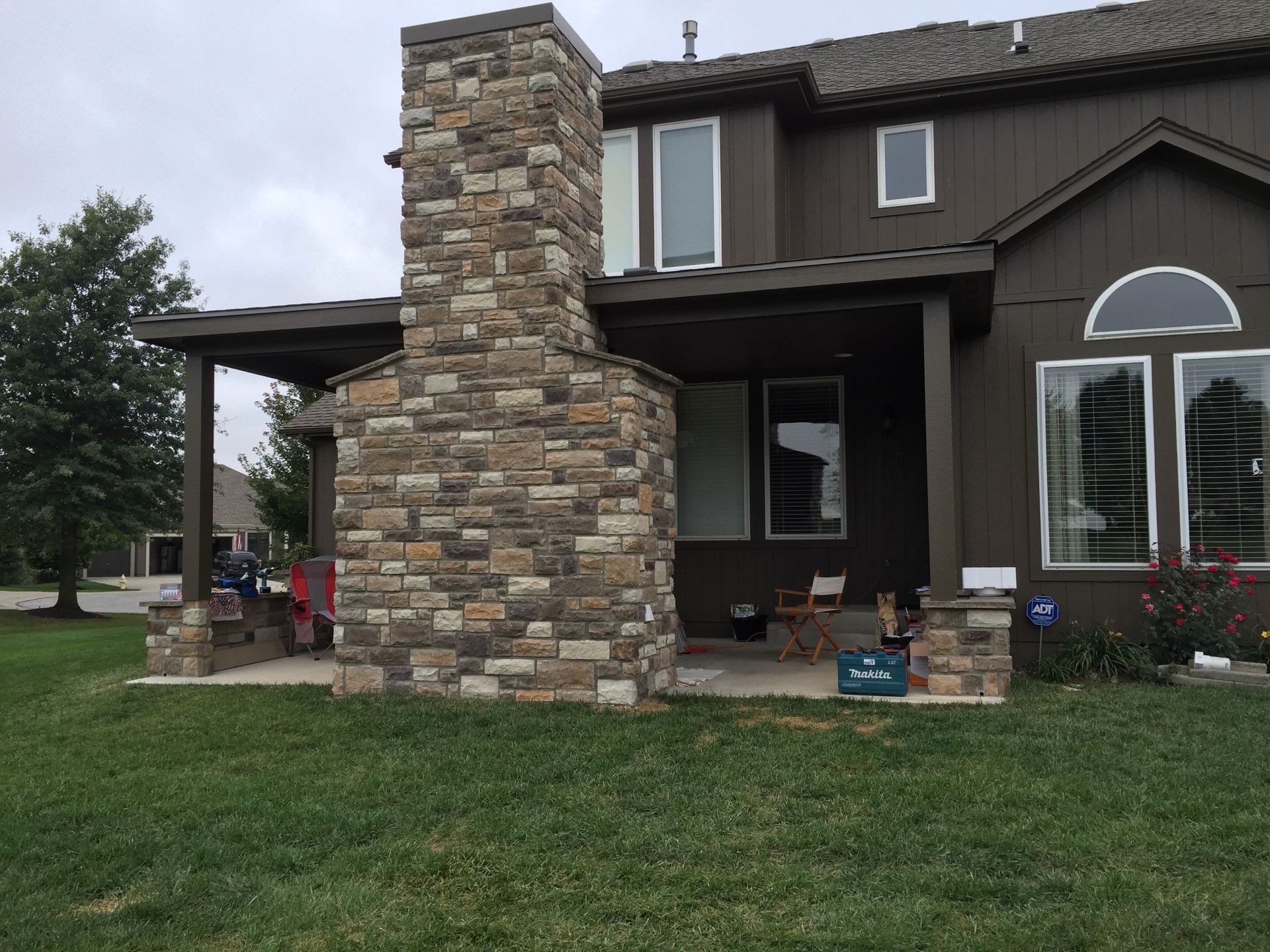 A brown house with a stone fireplace on the front porch