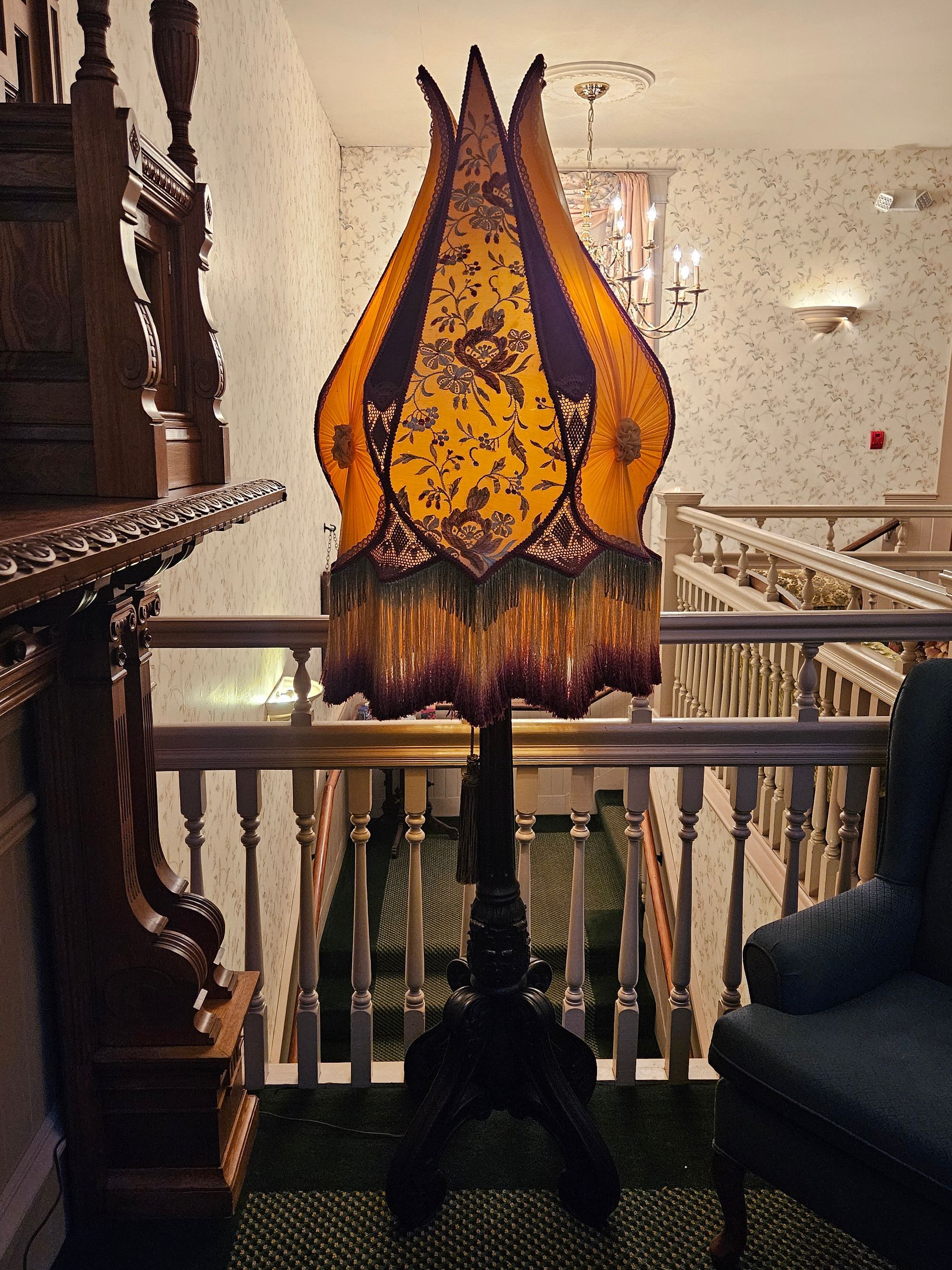A lamp on a stand in a room next to a chair
