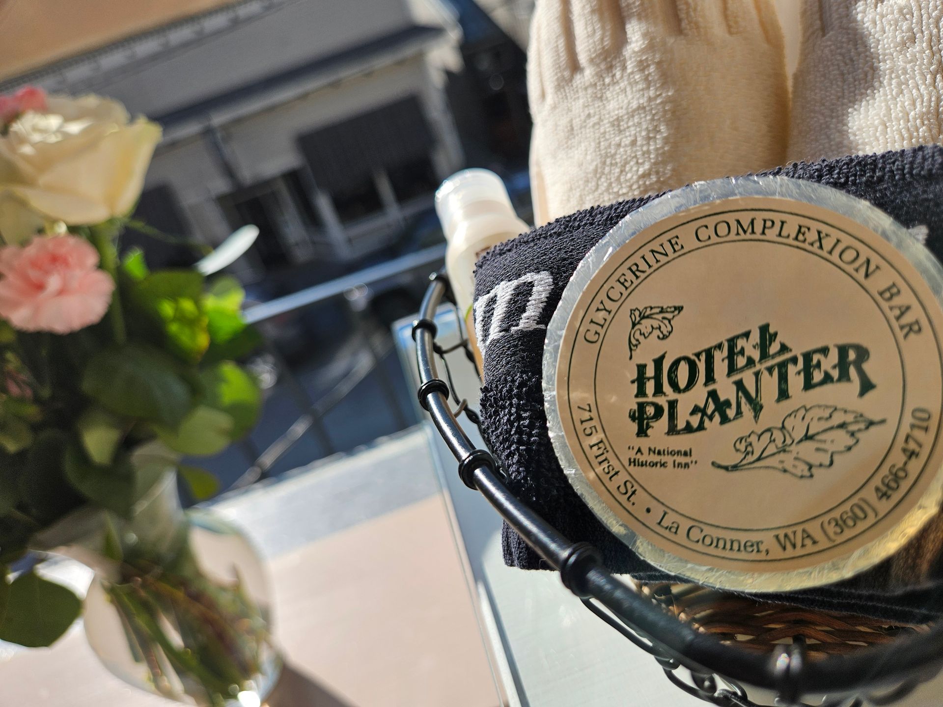 A container of hotel planter glycerine complexion bar sits on a table next to a vase of flowers.