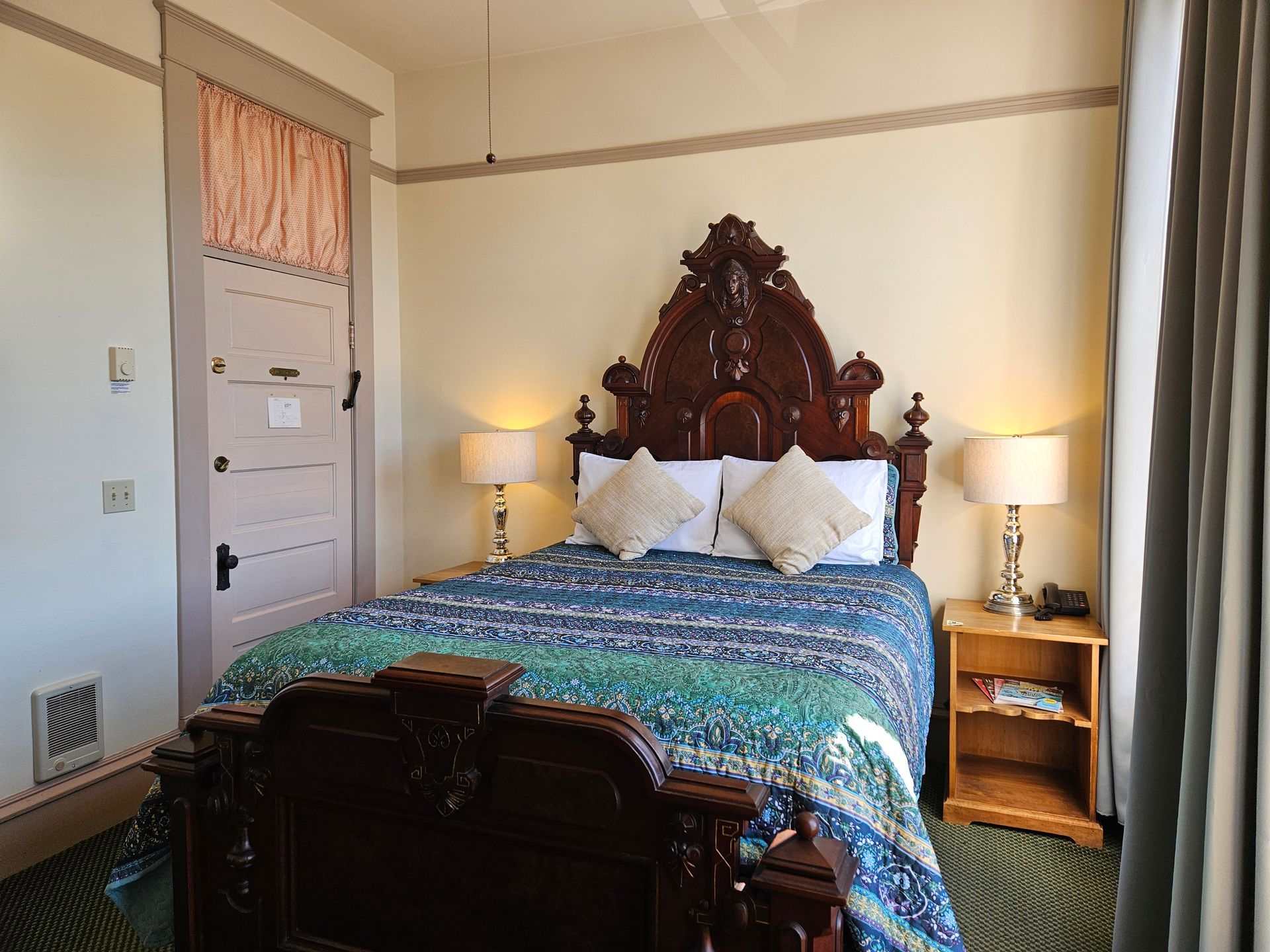 Bedroom with ornate wooden bed frame, bedside tables with lamps, and patterned bedspread.