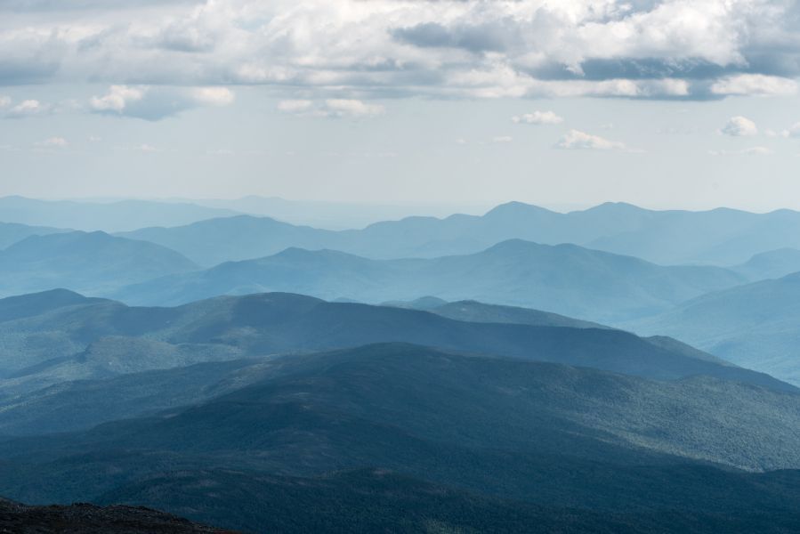 Layers of blue-hued mountains under a cloudy sky, creating a hazy, atmospheric vista.