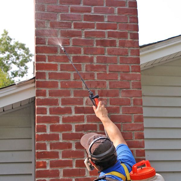 a man is sitting on top of a roof fixing a chimney .