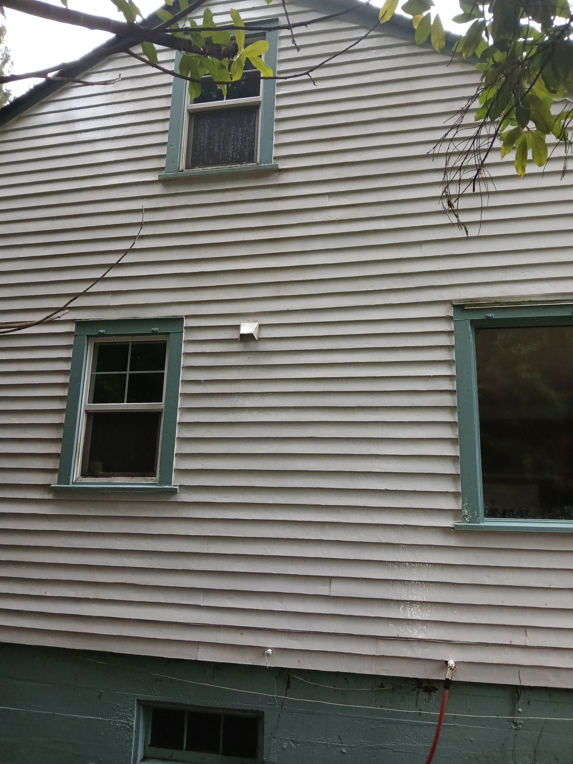 After: The same house exterior, now sparkling clean with bright, spotless siding and windows, highlighting a refreshed appearance.