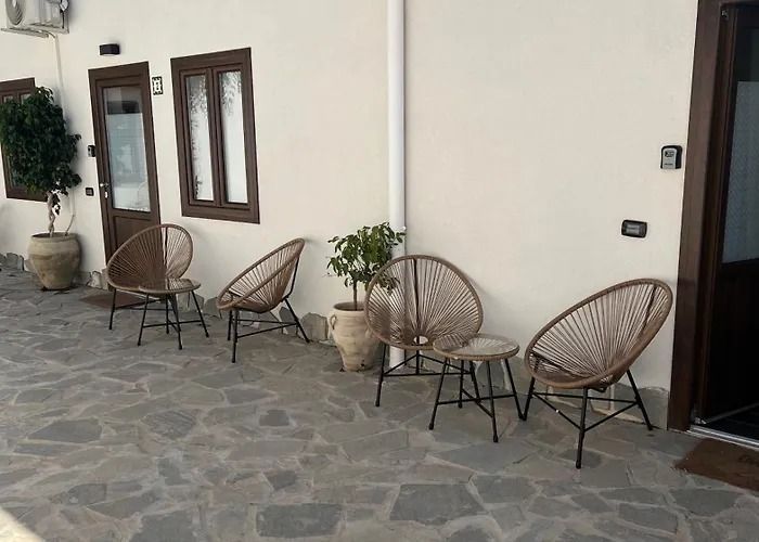 Patio esterno con sedie in vimini e tavolini lungo una parete color crema dell'edificio.