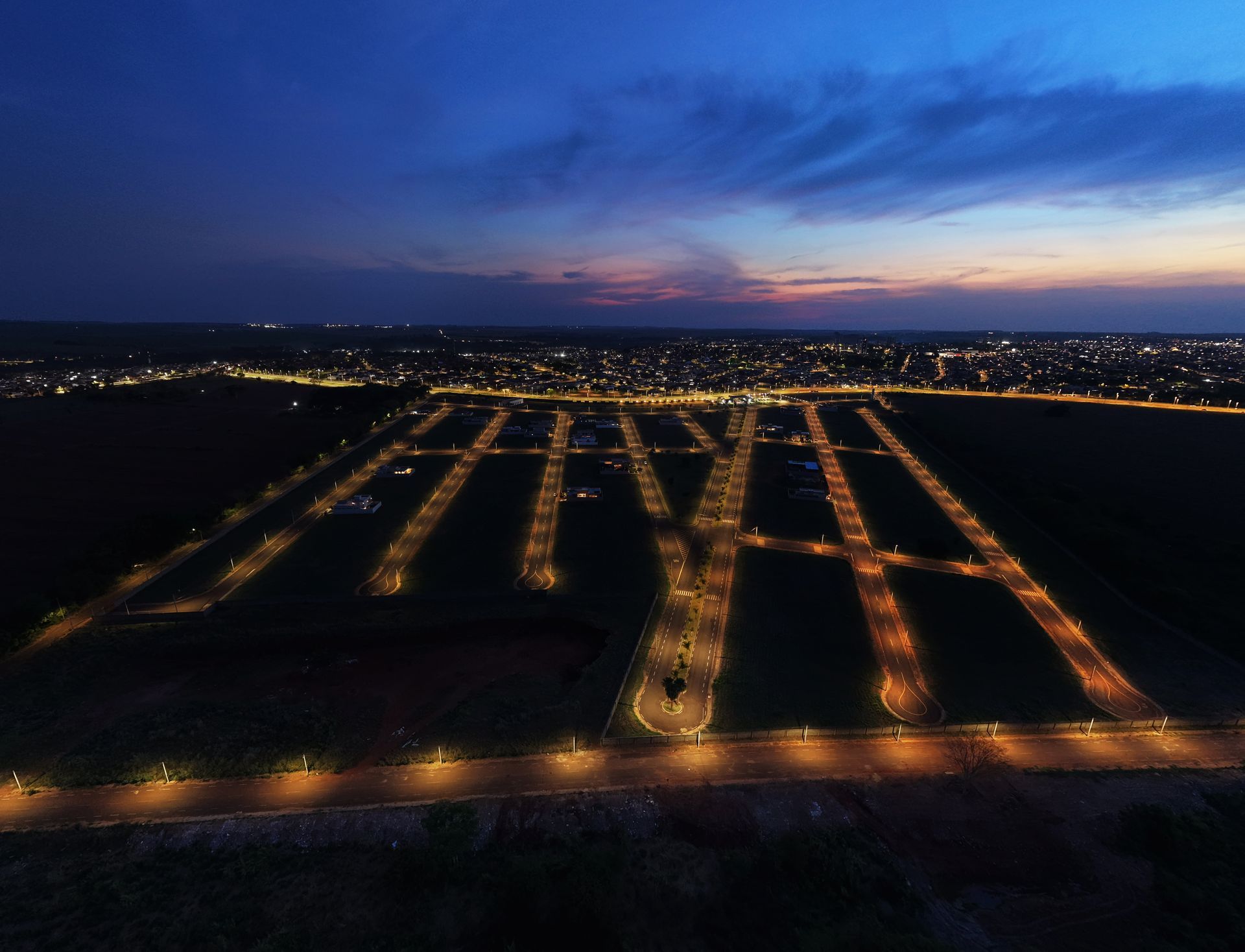 Vista aérea de um conjunto habitacional bem iluminado, formando a sigla 