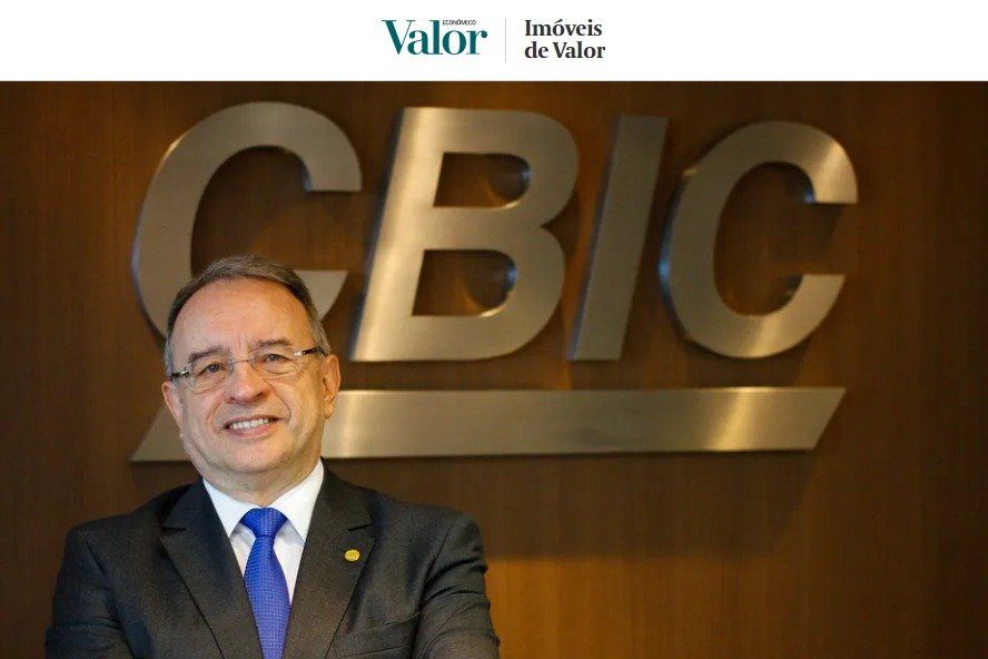 Homem de terno em pé diante do logotipo da CBIC.