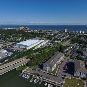 Aerial view of a coastal town with a marina, buildings, streets, and the ocean under a clear blue sky