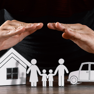 Hands shielding paper house, family, and car icons on black background