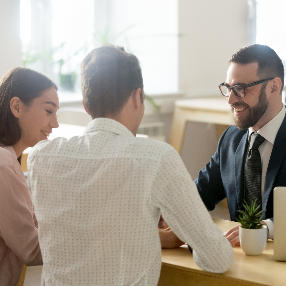 Three coworkers smiling during a meeting at a bright office table