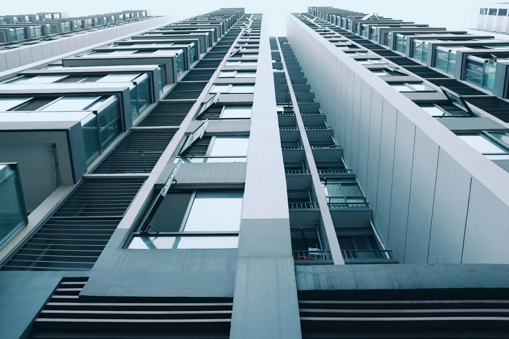 Looking up at modern high-rise apartment buildings with balconies and windows