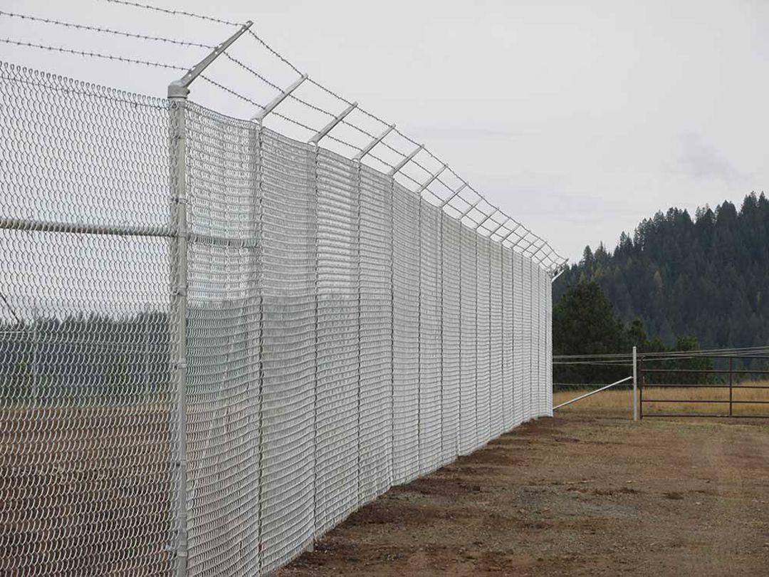 A chain link fence with barbed wire on top of it
