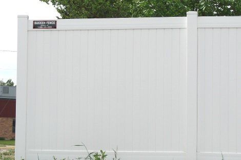A white fence with a sign on it that says ' emerald fence '