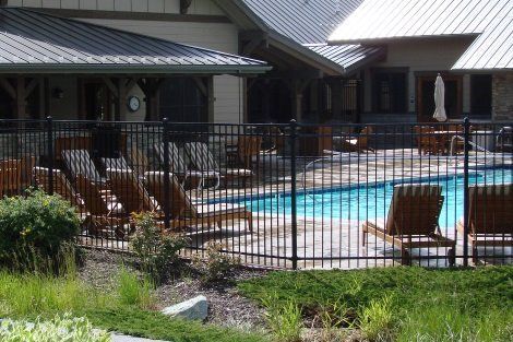 A large swimming pool surrounded by chairs and a fence.