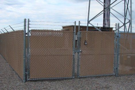 A chain link fence with a gate in front of a tower.