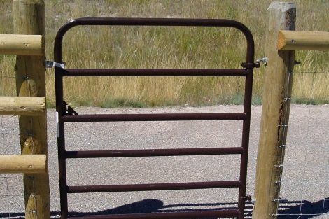 A brown gate with a wooden post behind it