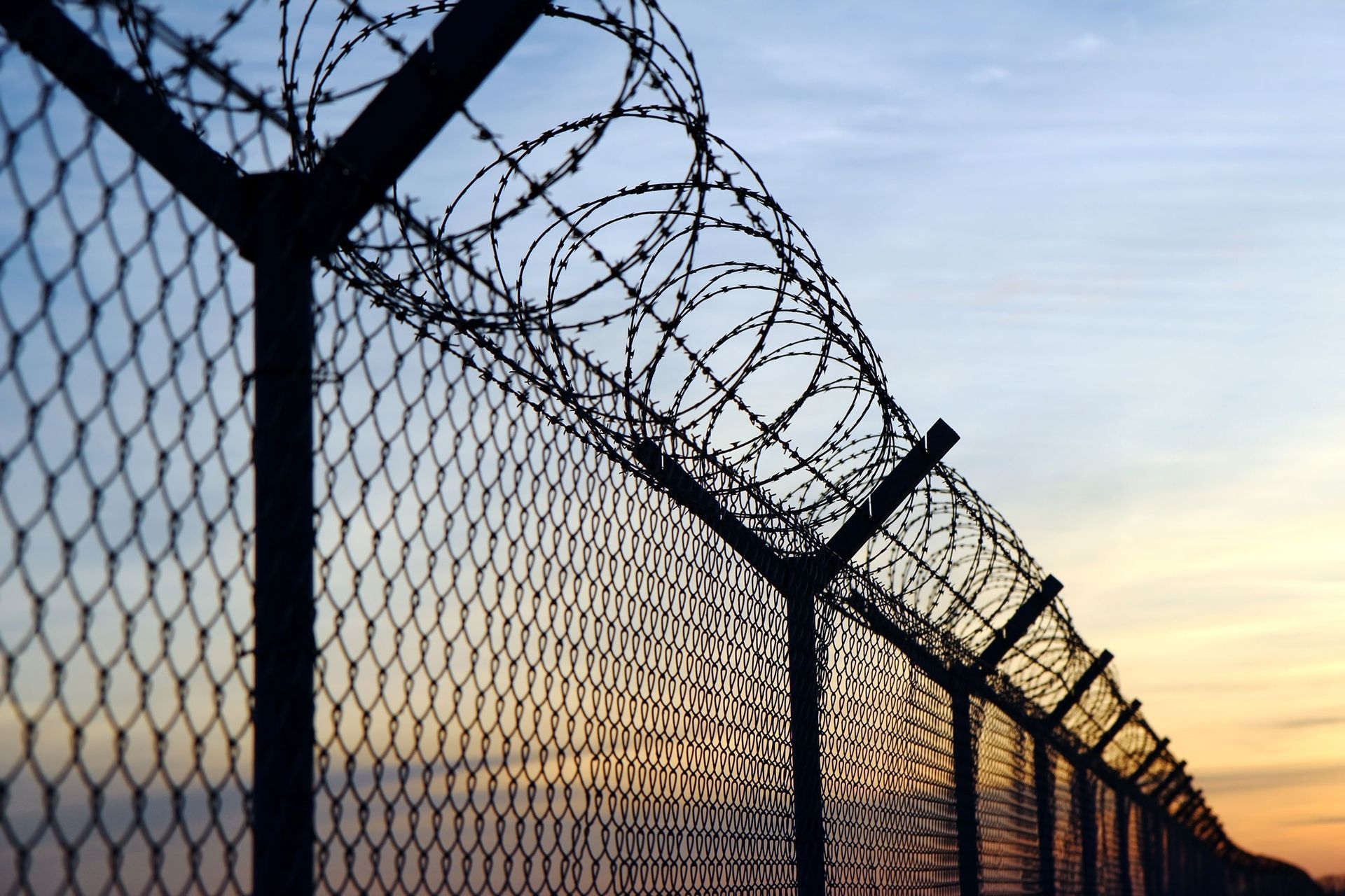 A barbed wire fence with a sunset in the background