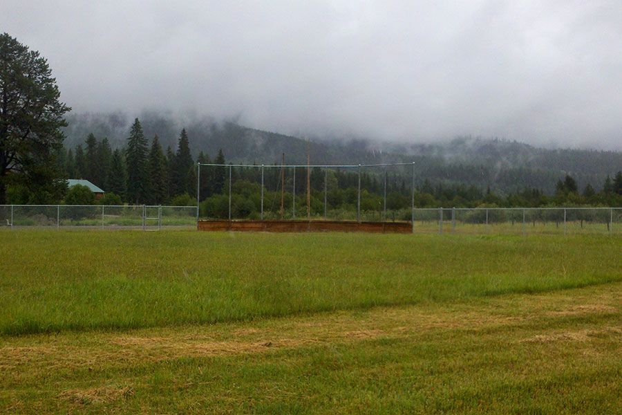 A baseball field with mountains in the background on a cloudy day