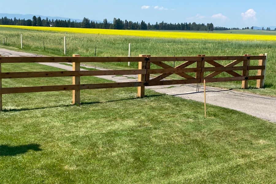 A wooden fence is in the middle of a grassy field.