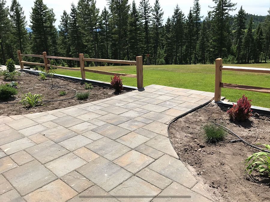 A patio with a wooden fence and trees in the background