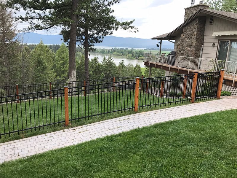 A wrought iron fence surrounds a lush green lawn in front of a house.