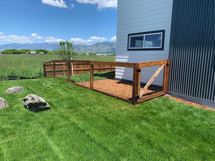 A wooden fence is sitting in the grass in front of a house.