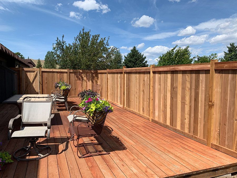 A wooden deck with a wooden fence and chairs.