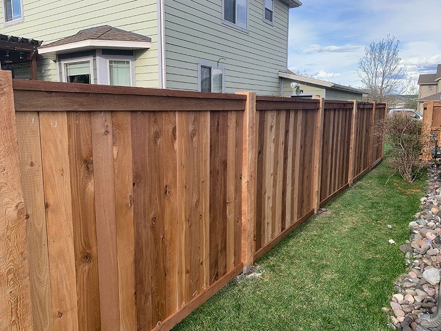A wooden fence is in the backyard of a house.