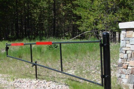 A black gate with a red stripe on it is sitting in the middle of a grassy field.