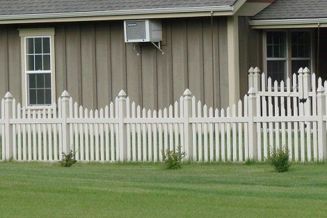 A white picket fence is in front of a house