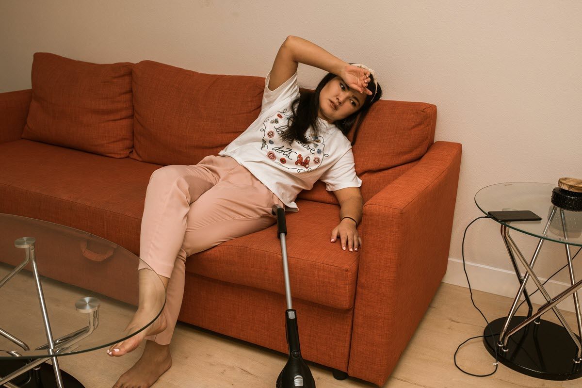 Woman reclining on an orange couch resting her arm on her forehead