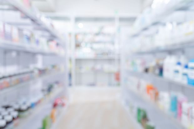 Un'immagine sfocata di una farmacia con scaffali pieni di medicinali.