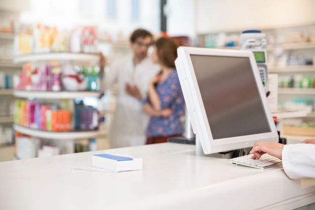 Un farmacista sta usando un computer in una farmacia.