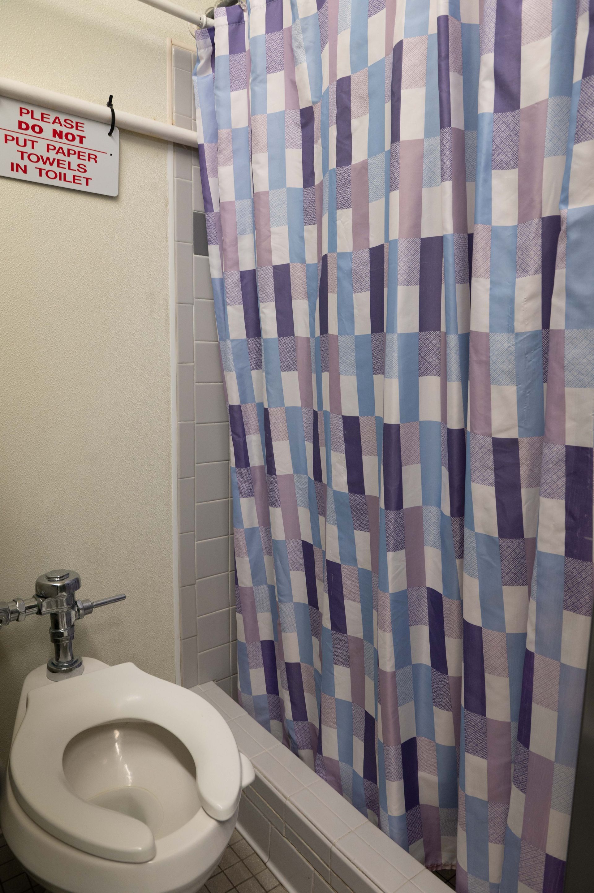Small bathroom with a toilet and a shower curtain with purple, blue, and pink geometric pattern.
