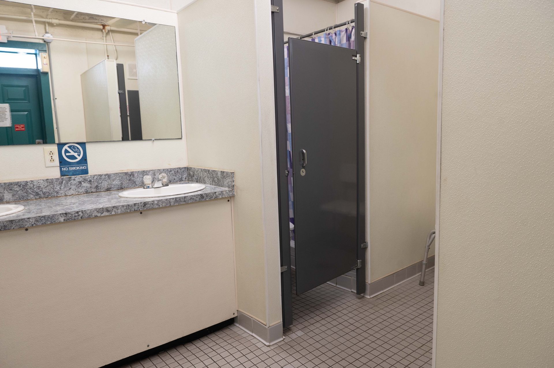 Public restroom interior with sink counter, mirror, and open stall door