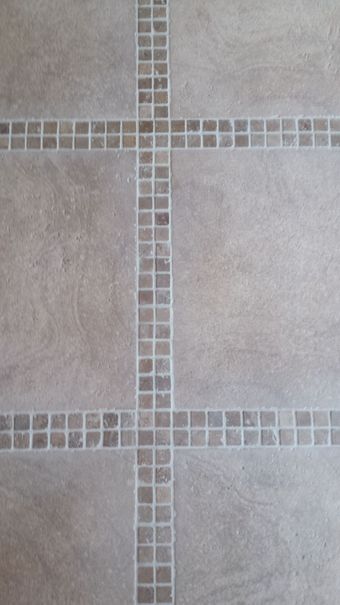 A black and white tiled floor in a bathroom with a drain.