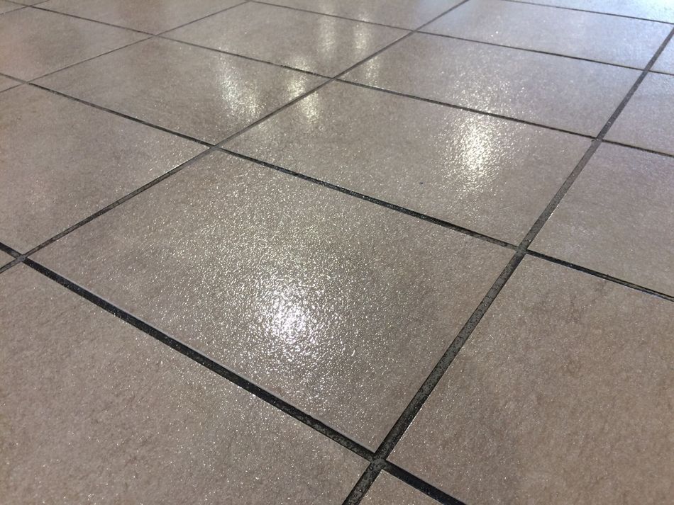 A shower stall with white tiles and a drain.