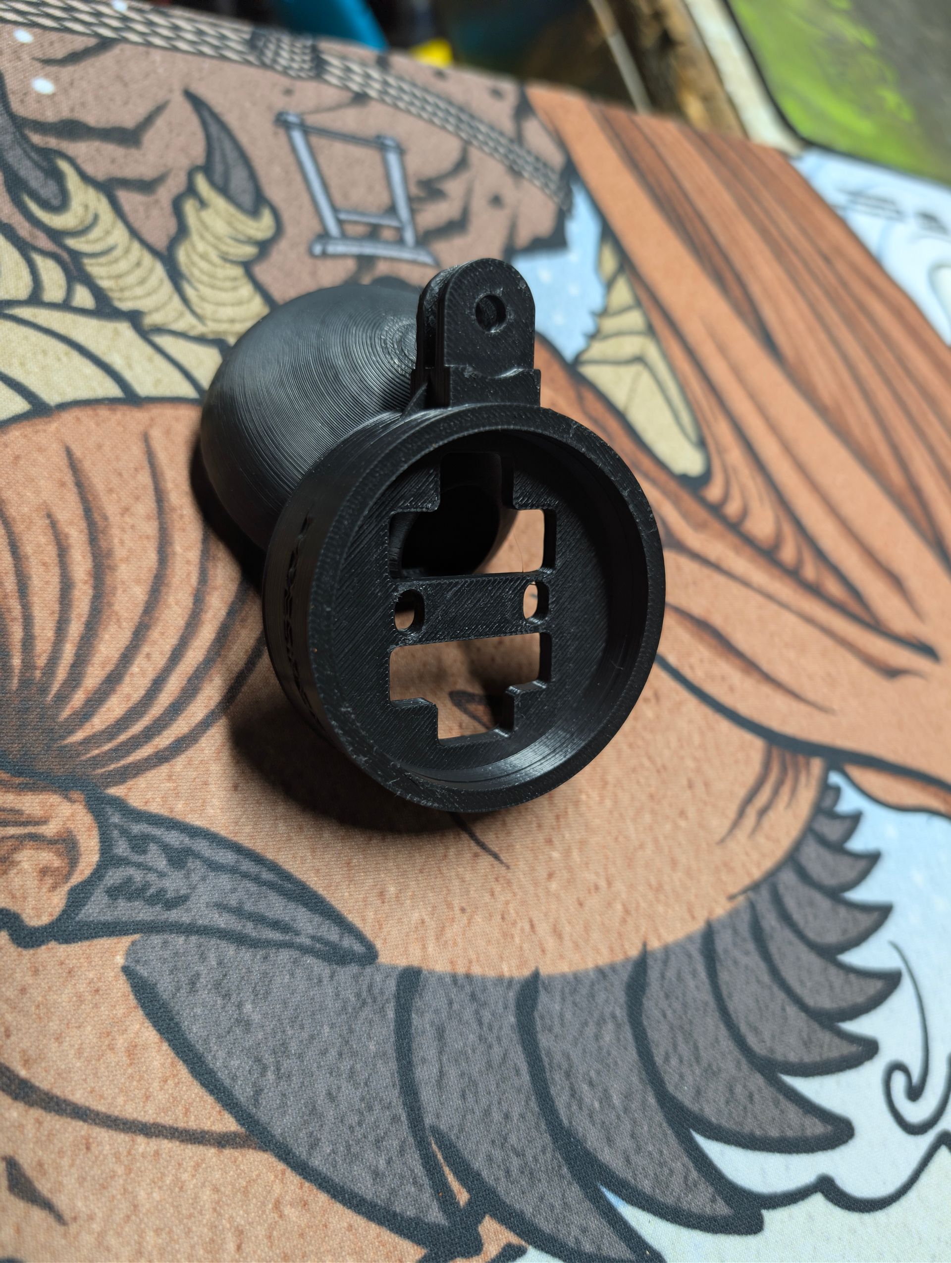 Close-up of a black gauge pod V2 circular plastic clip on patterned fabric surface