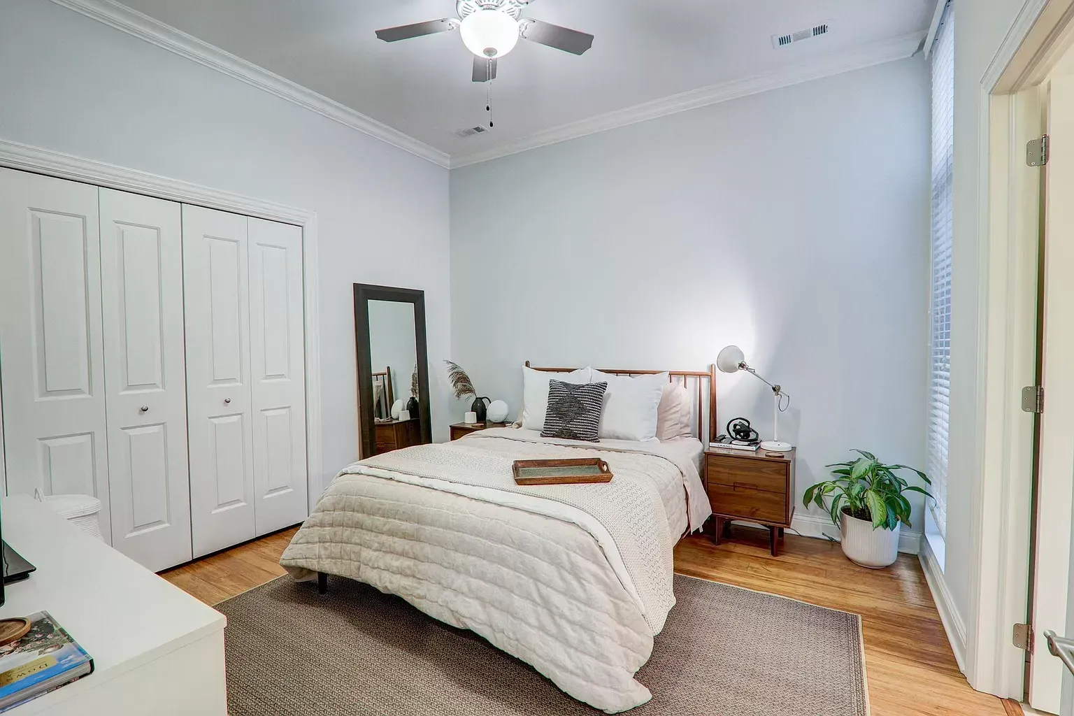 a bedroom with a bed , nightstand , mirror and ceiling fan .